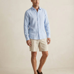 Men wearing light blue linen shirt styled with neutral shorts