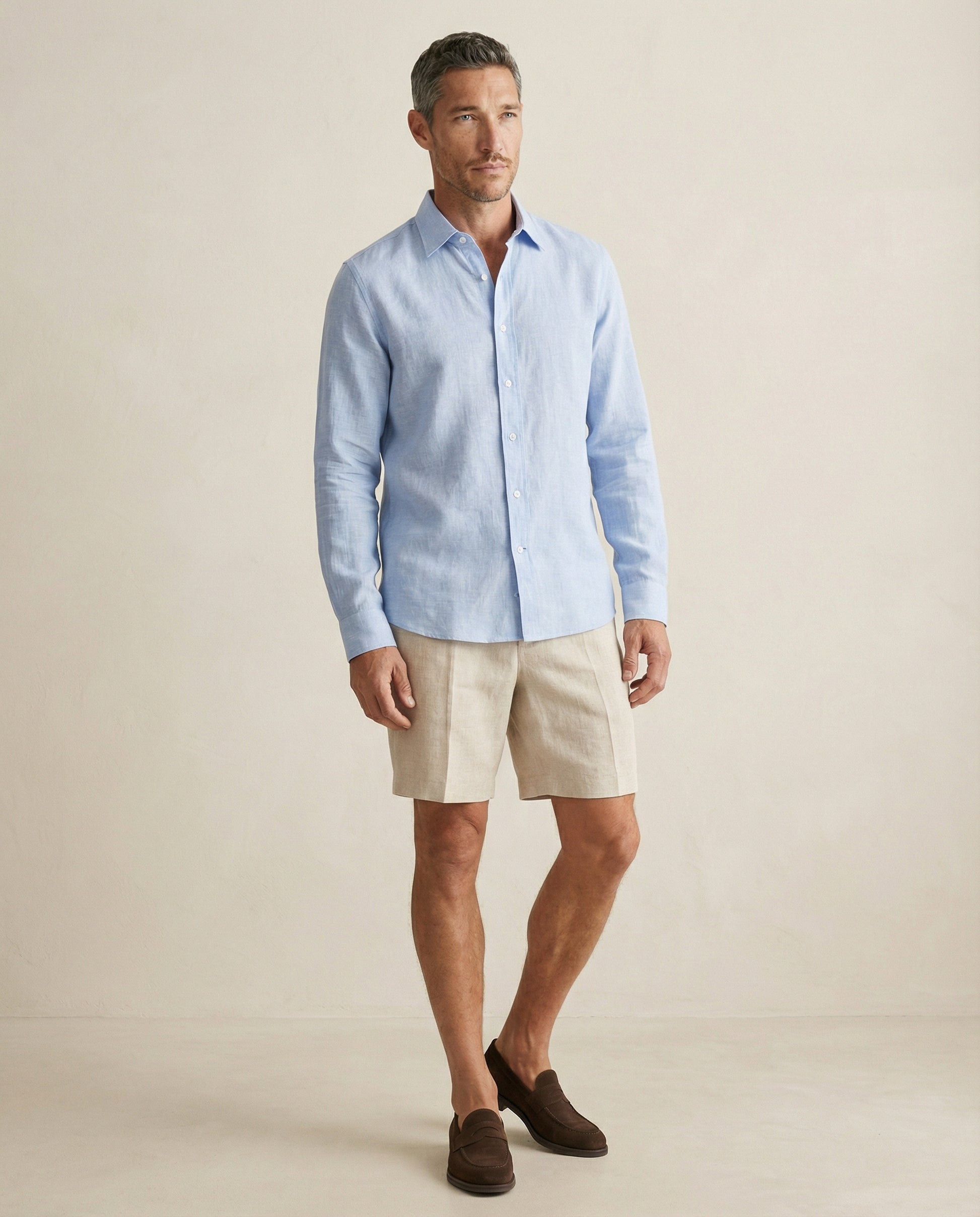 Men wearing light blue linen shirt styled with neutral shorts