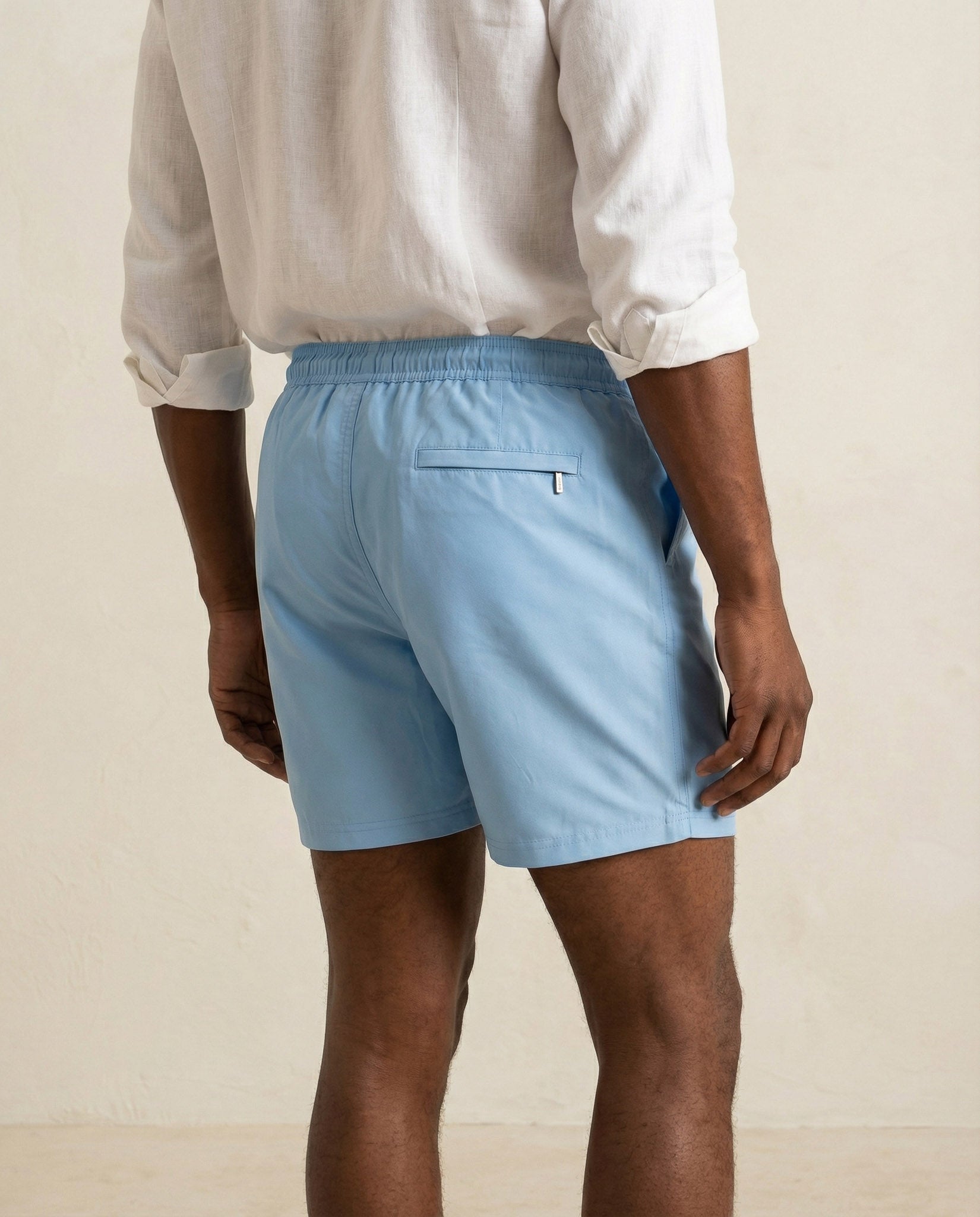 Back view of Lumari light blue swim shorts featuring welt back pocket.