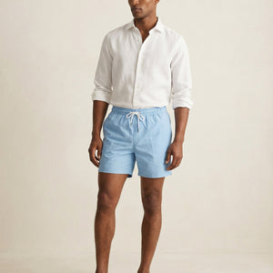 Model wearing Apprivio Lumari light blue swim shorts with white linen shirt, full body view
