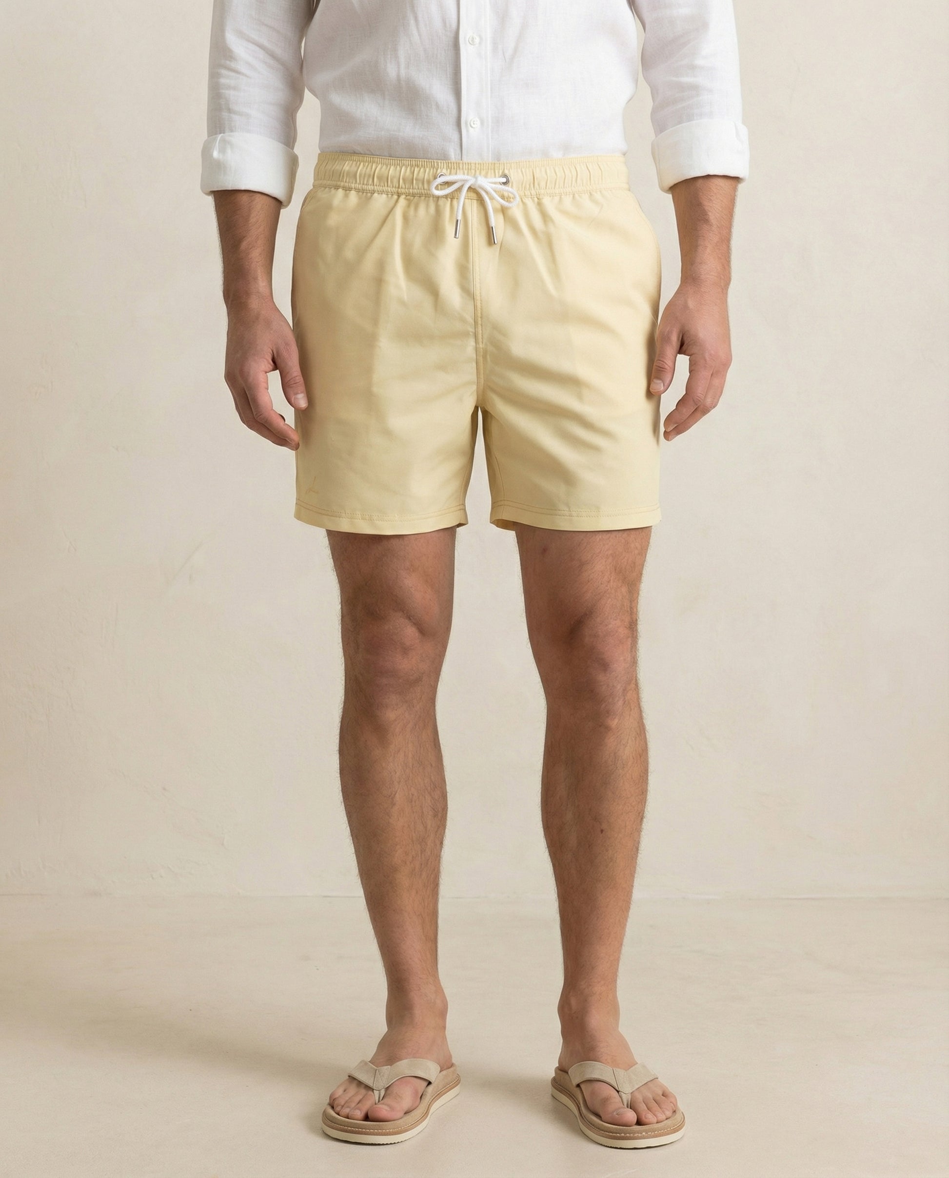 Lumari light yellow swim shorts front view on model, tailored mid-length silhouette.