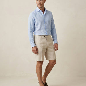 Men’s natural linen shorts worn with light blue linen shirt, full outfit view