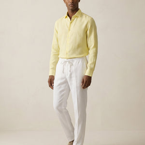 Men’s pearl white linen trousers worn with yellow linen shirt, full outfit view