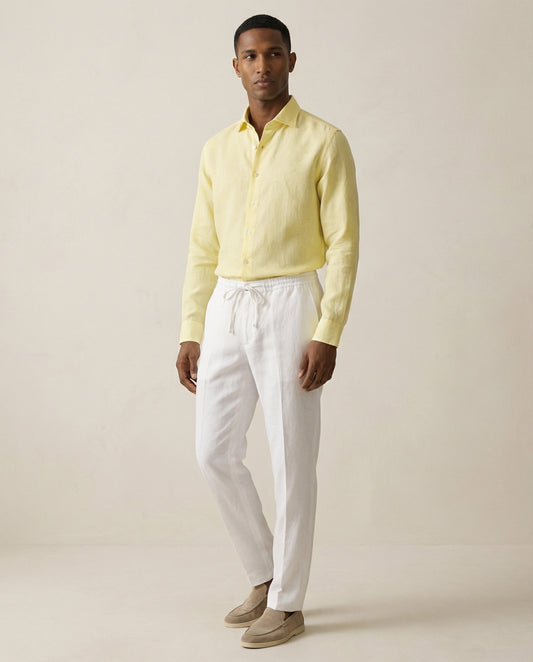 Men’s pearl white linen trousers worn with yellow linen shirt, full outfit view