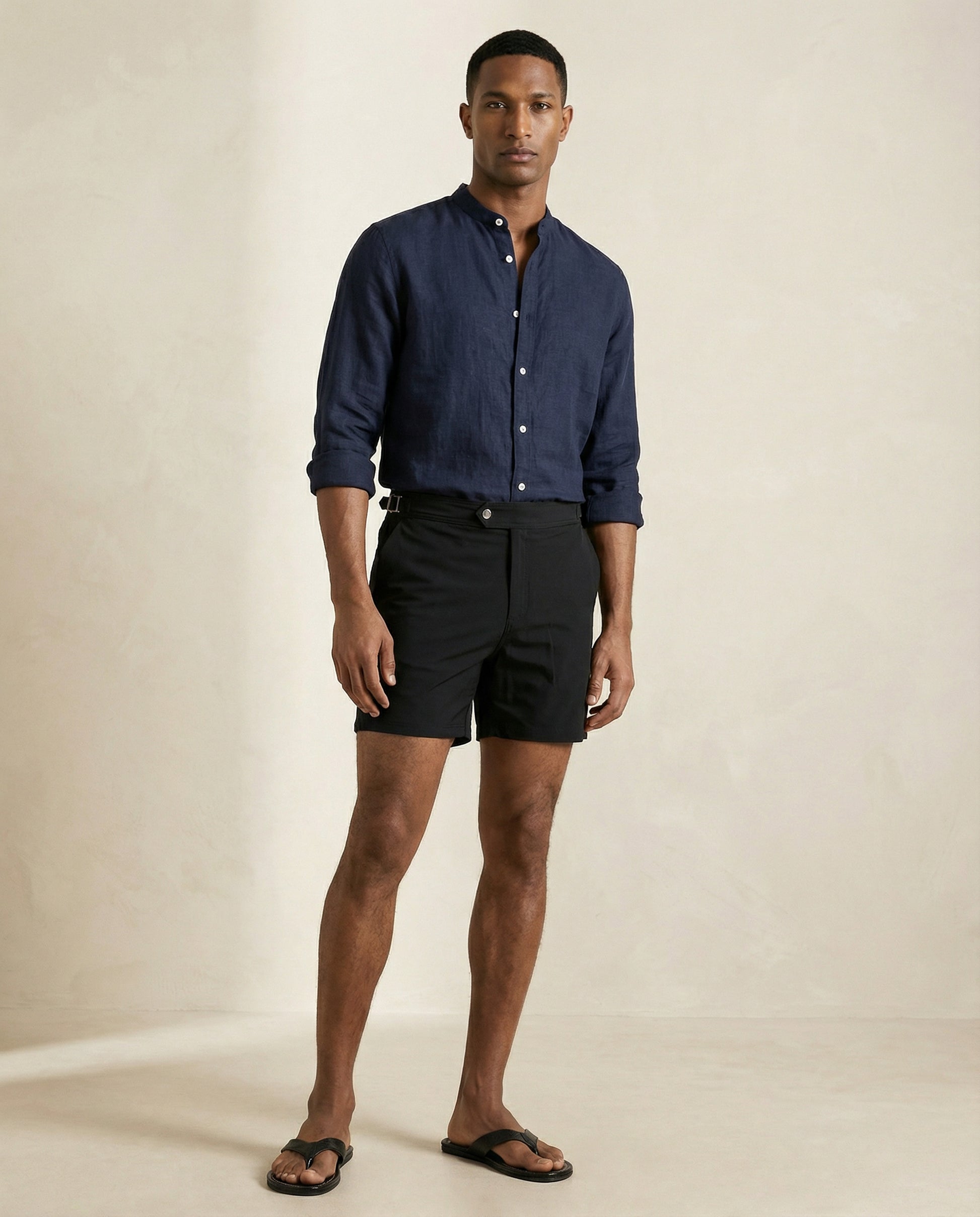 Model wearing Apprivió Riviera black tailored swim shorts with side buckle waistband and linen shirt.