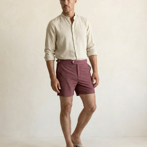 Model wearing Riviera burgundy tailored swim shorts with adjustable side buckle, styled for elevated resort wear.