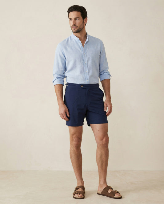 Apprivió Riviera navy swim shorts with side buckle waistband, styled with linen shirt for refined summer look.