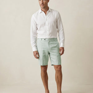 Men’s sage green linen shorts worn with white linen shirt, full outfit view