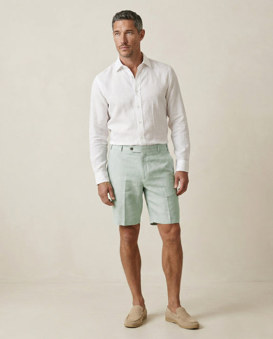 Men’s sage green linen shorts worn with white linen shirt, full outfit view